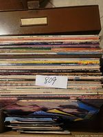 Top view of metal storage container filled with LP vinyl albums showing colorful spines and wear consistent with vintage items.