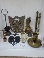 Photo shows all metal items together with eagle motifs, candle holders, iron wall sconces, figurines, and ceramic face.