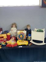 Overview of the vintage children's toys including dolls, a toy piano, a colorful spinning toy, and a wooden rocking chair.