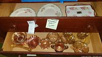Drawer showing three floral decorative plates and several carnival glass pieces in golden iridescent finish.