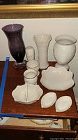Five vases and four trinket dishes displayed on a wooden surface including a purple glass vase, white Woodland vase, and Princess Diana vase