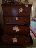 Front view of the four-drawer wooden dresser with visible wear and contents inside some drawers.
