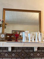Full view of the large rectangular mirror on a wall showing beveled edges and gold tone wood frame.