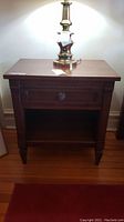 Frontal view of wooden nightstand with lamp on top