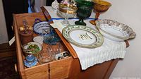 Full view of the servingware and trinket boxes displayed on a wooden side table with some items inside an open drawer.