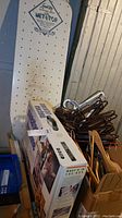 Full view of Speed Top metal ironing board, boxed sweater machine, and hangers clustered in cardboard box.