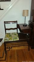 Front-right angled view of the wooden telephone table with attached bench and lamp on table surface.