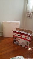 View of white wedge pillow next to Canon Pixma MG2522 printer box on wooden floor.