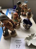 Overview of all five Hummel figurines and the small blue vase with leaf decorations.