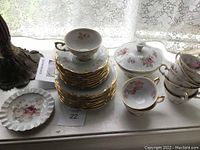Overall view of stacked eight tea cups, saucers, and dessert plates, plus covered serving dish and one additional dessert plate.