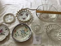Top view of four floral porcelain candy dishes and three clear glass bowls displayed on white cloth with a ruler for scale.
