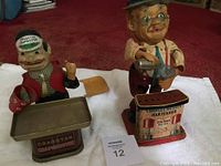 Photo showing both the Charley Weaver Bartender and the Cragstan Crapshooter toys side by side on a towel, highlighting their size and condition.