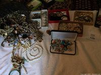 Wide view of the jewelry assortment on a white towel showing necklaces, earrings, pins, bracelets in boxes and scattered loose.