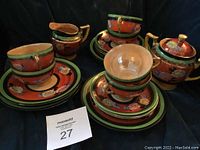 Full set including cups, saucers, creamer, sugar bowl, and stirring spoons arranged on a dark surface