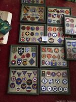 Overview of multiple wooden frames containing various military patches including divisional and Air Force patches laid out on carpet.