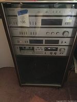 Front view of stacked Panasonic audio components in glass front cabinet showing control panels from top to bottom.