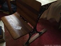 Side view of antique wooden school seat and desk showing wooden slatted seat and ornate cast iron sides.