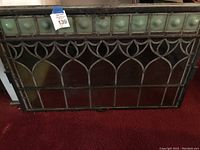 Front view of stained glass window panel laid on red carpet