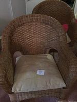 Front view of one wicker club chair with beige cushion showing overall condition and design