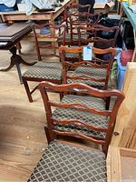 Full view of six wooden dining chairs with upholstered seats arranged in room with wood flooring