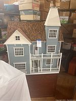 Front exterior view of blue and white dollhouse on wooden table