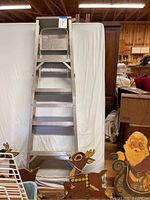 Front view of aluminum 4 step ladder with wide steps, standing upright.