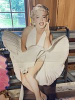 Life-size cardboard standee of Marilyn Monroe in white dress pose, part of celebrity party decor.