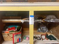 Wicker basket with rain ponchos and two 1000-piece puzzles on cabinet shelf.