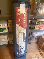 Photo of rolled-up Quest dome canopy in carrying case showing branding and size details.