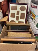 Box with multiple empty picture frames of various sizes and a multi-opening mat frame with spaces for small photos/artworks in multiple oval and rectangular openings.