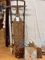 Photo showing the large wooden sled with metal runners, two pairs of ice skates, and part of the handmade wooden Santa Claus and reindeer decoration.