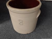 Front view showing the entire antique stoneware crock with number '2' on the side and brown glazed interior.