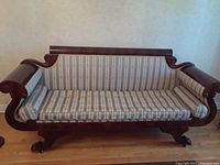 Front view of antique settee showing rolled arms, wooden frame and striped upholstery