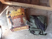 Pair of green chest waders next to the original box on a wooden floor.