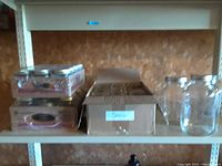 Shelf with loose glass mason jars, shrink-wrapped packs of Golden Harvest jars and a small dark glass bottle.