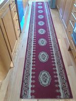 Full length view of red runner rug positioned in a kitchen space on hardwood floor