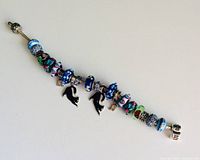 Full view of silver snake chain bracelet laid flat showing all beads and charms