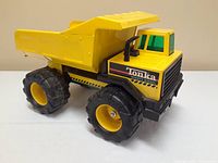 Side view of the yellow Tonka Mighty Diesel toy dump truck showing the large tires and dump bed.