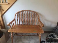 Full front view of wooden spindle back hall bench showing seat, arms, and legs