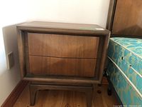 Front view of one bedside table next to mattress