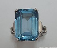 Close-up front view of the 10K white gold ring with a large rectangular cut blue topaz synthetic spinel gemstone.