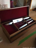 Open walnut case showing carving knife and carving fork inside with red felt lining