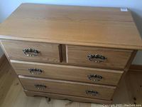 Full front view of the oak finished chest of drawers showing the drawer layout and metal handles.