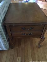 Wooden French provincial style end table showing top surface design, drawer front and cabriole legs.