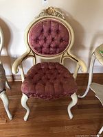 Front view showing the cream painted wood frame with carved floral detail and rounded tufted rose upholstery on backrest and seat.