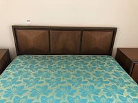 Front view of the wooden headboard with mattress showing floral patterned mattress cover.