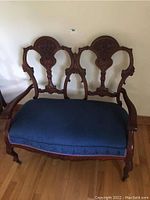 Full view of the wooden parlour settee with blue upholstered seat and carved backrest and arms.