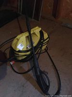 Yellow Karcher pressure washer with black hose and spray gun laid on floor