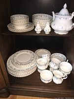 Top shelf showing teapot, salt & pepper shakers, stacks of plates and bowls.