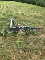 Front view showing weathered metal blade with faded blue paint and A-frame hitch